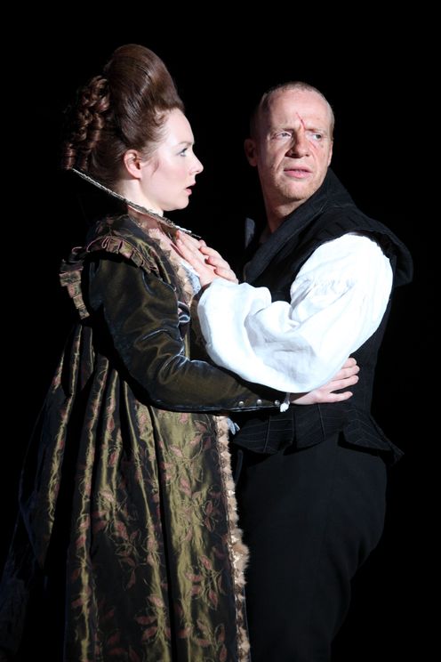 Lady Macbeth clutches Macbeth's waist while he turns his gaze away from her.